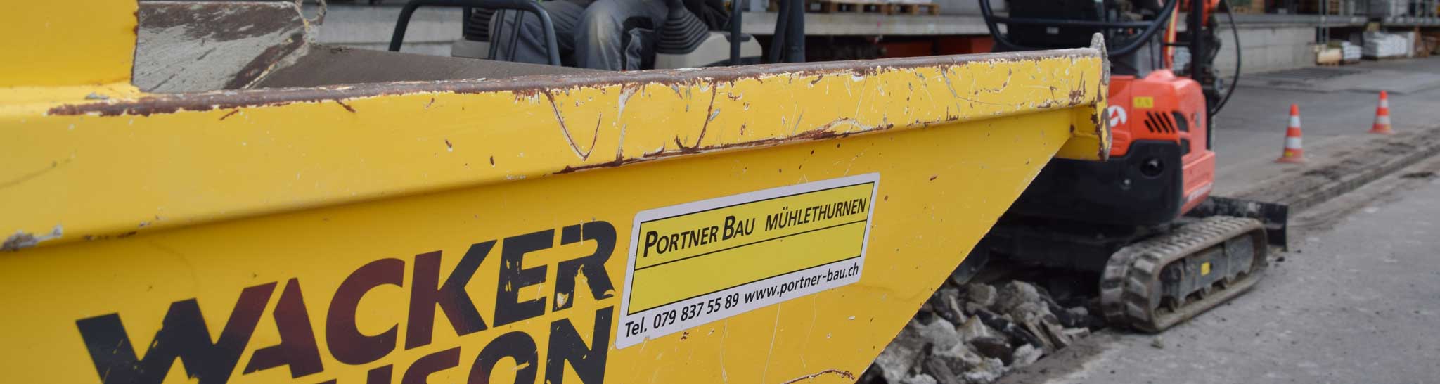 Gelber Dumper mit dem Kleber von Portner Bau Mühlethurnen.