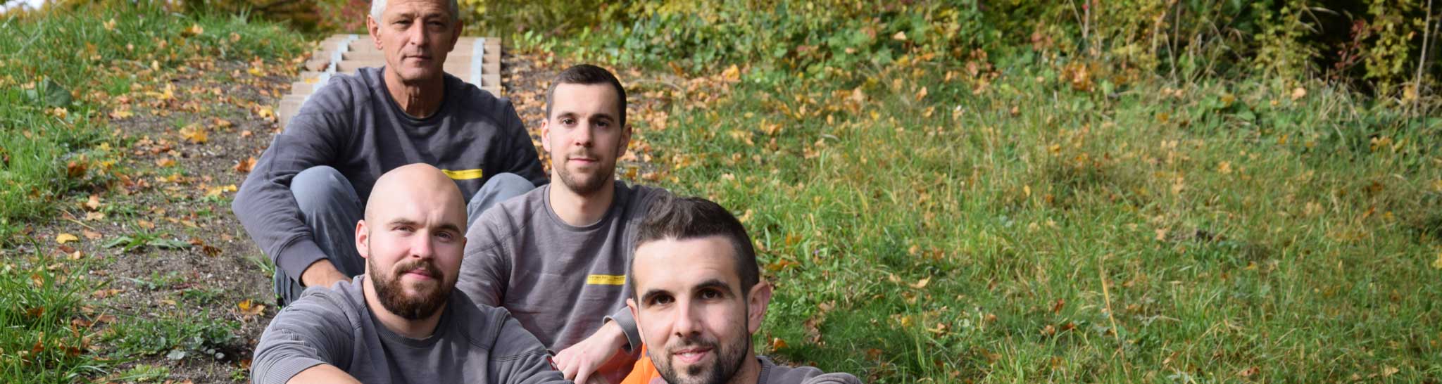 Das Team sitzt auf einer Treppe in einem herbstlichen Hang.
